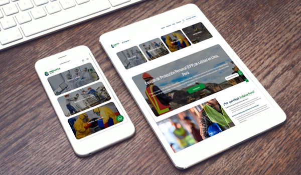 Un smartphone y una tablet sobre una mesa de madera mostrando el diseño adaptativo de una página web profesional.
